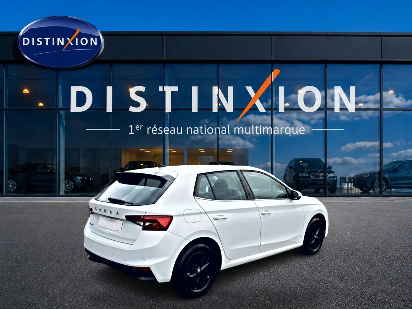 Vue 3/4 arrière droite d'une Skoda Fabia blanche 2025 avec jantes noires, stationnée devant une vitrine Distinxion.