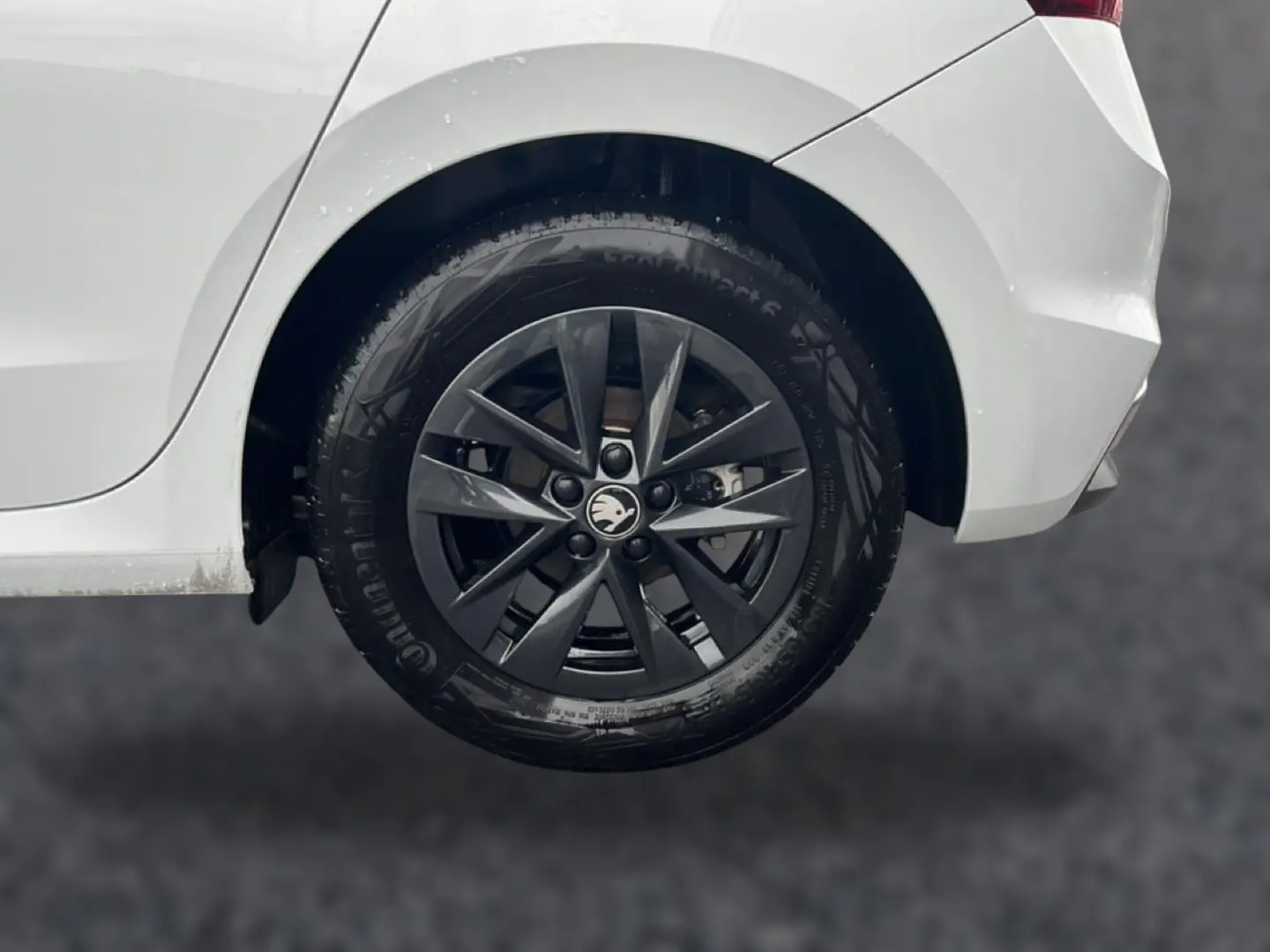 Gros plan sur la roue arrière droite noire avec jante alu gris foncé d'une Skoda Fabia blanche 2025.