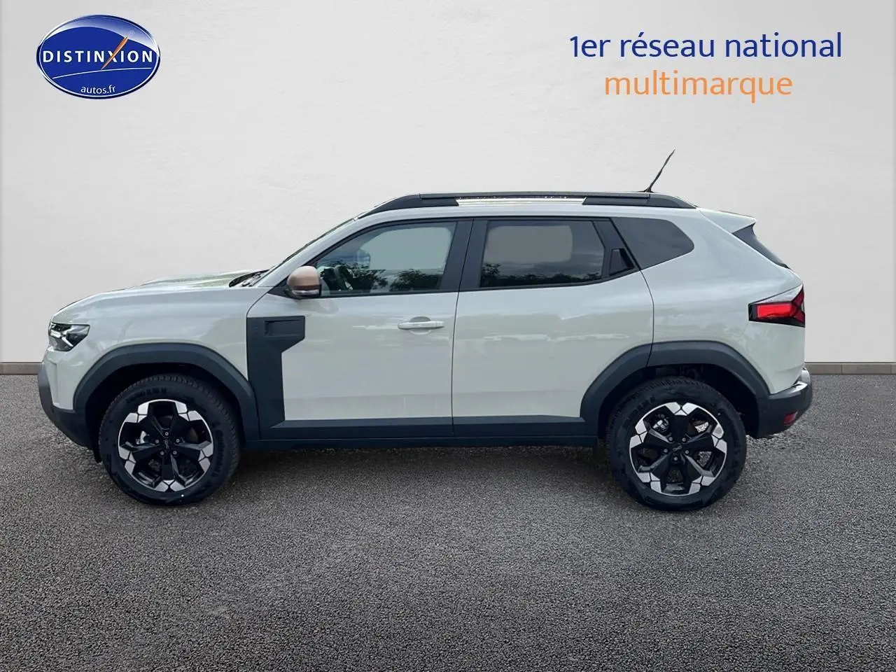 Profil côté gauche du Dacia Duster 2025 couleur Sandstone avec jantes alu et barres de toit noires.