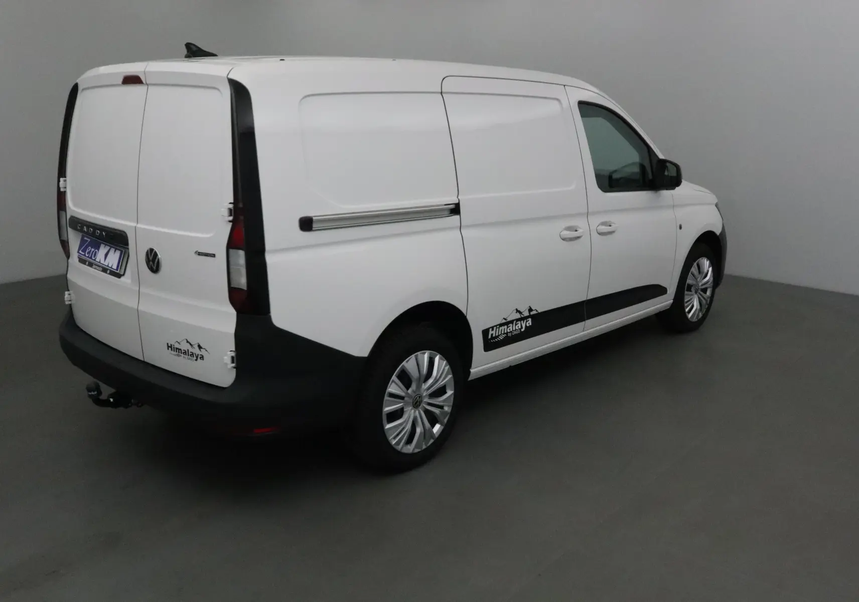 Volkswagen Caddy Maxi blanc en 3/4 arrière droit avec logo Himalaya et attelage visible sur fond neutre.