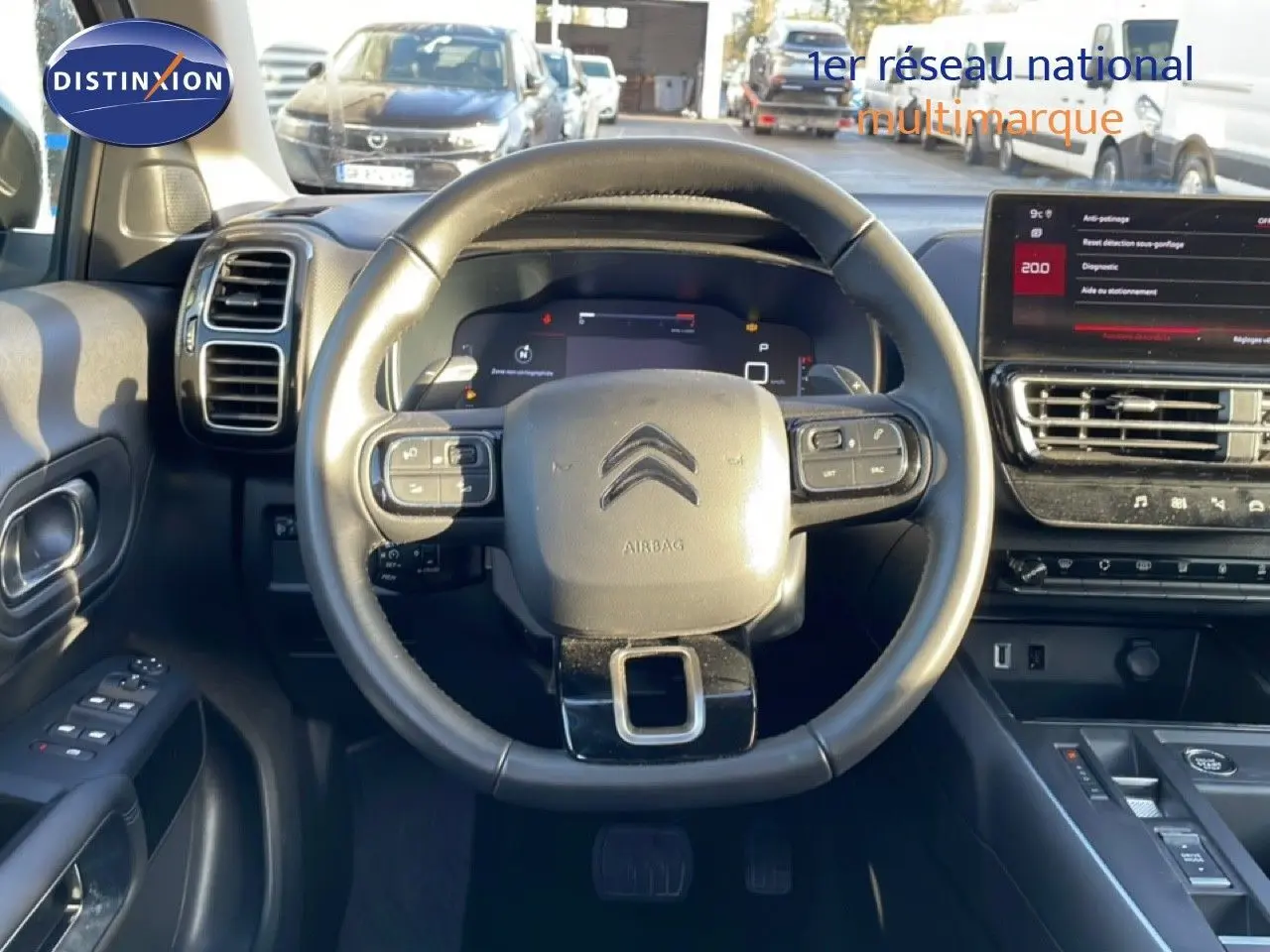 Vue intérieure centrée sur le volant cuir noir d'une Citroën C5 Aircross 2025, avec tableau de bord digital et écran tactile.