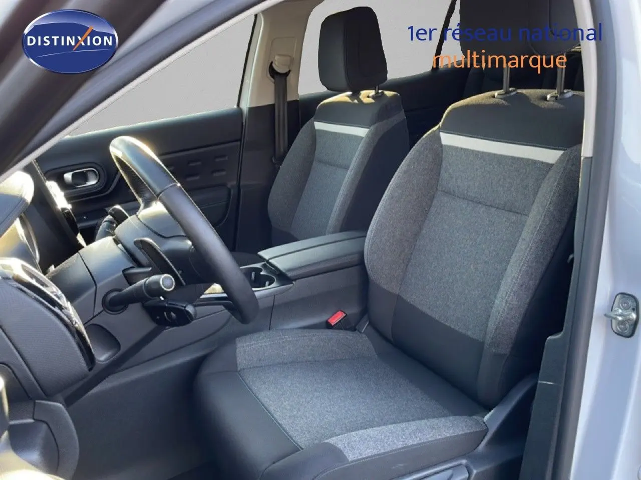 Vue intérieure côté conducteur du Citroën C5 Aircross blanc, montrant les sièges tissu et cuir gris et le volant multifonction.