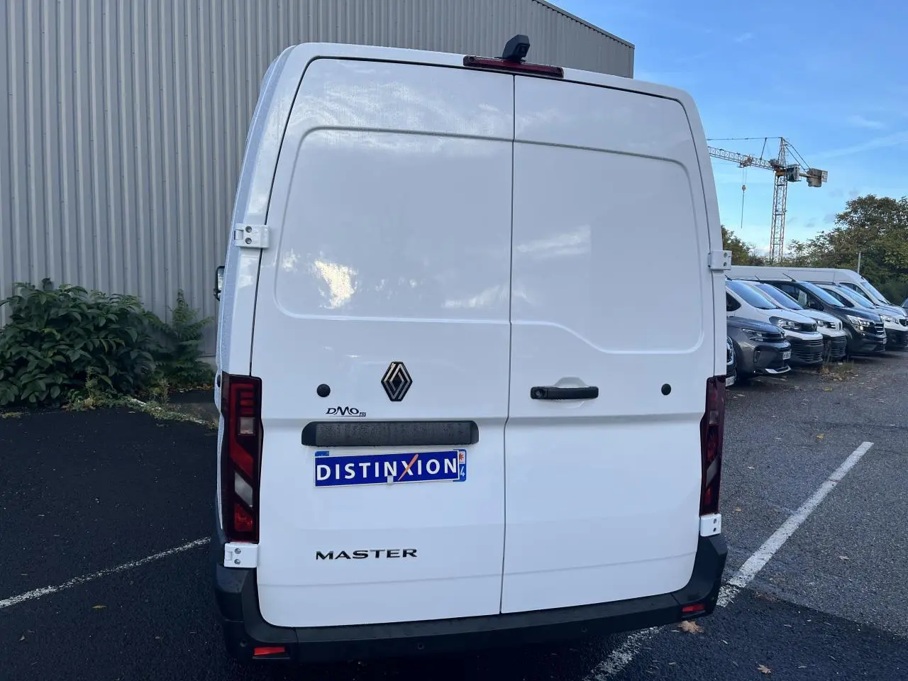 Vue arrière d’un Renault Master blanc 2025 avec portes battantes et logo noir sur parking extérieur.