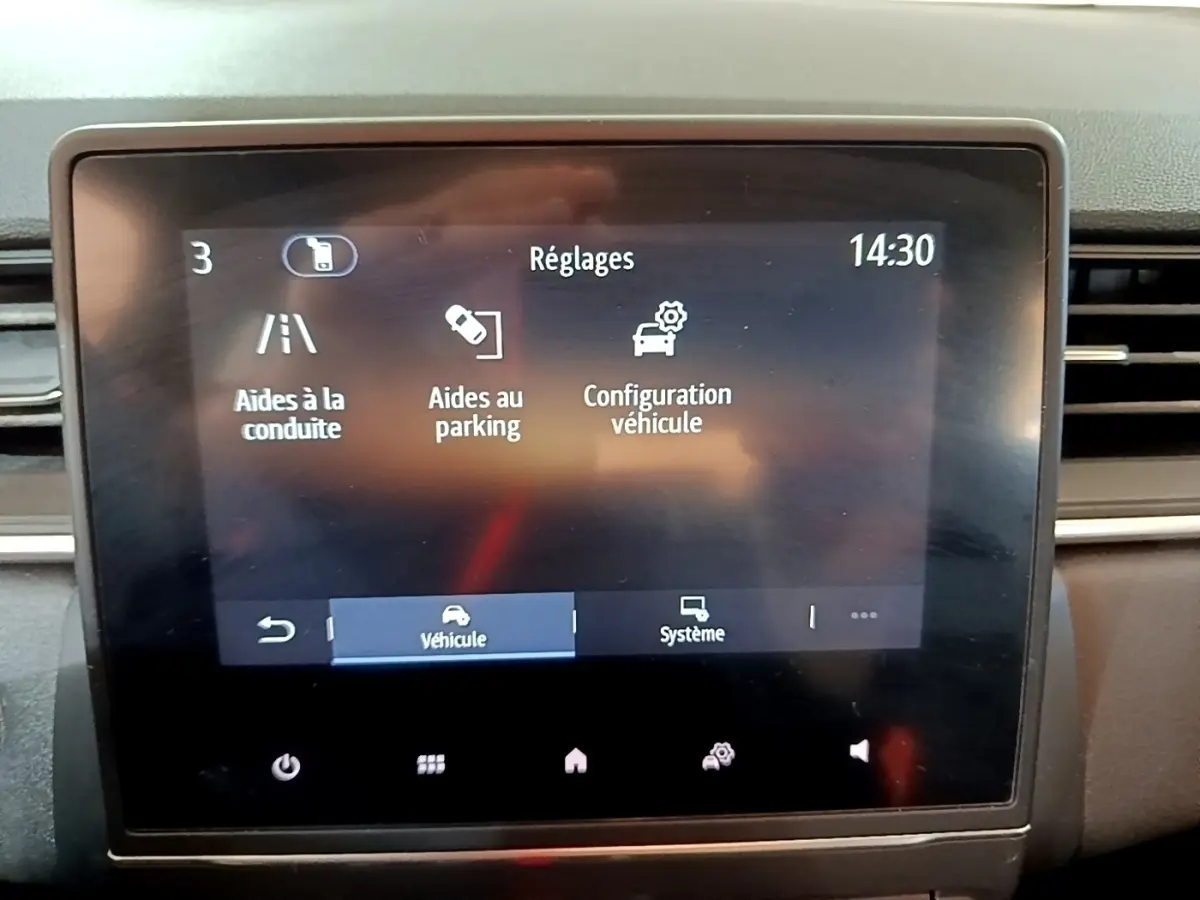 Écran tactile central du tableau de bord du Renault Captur Business noir, affichant les réglages d’aides à la conduite et au parking.