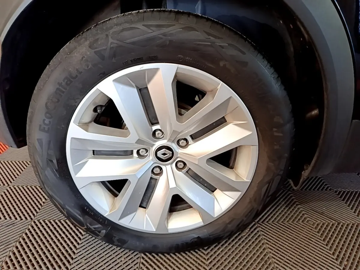 Gros plan sur la roue arrière gauche d’un Renault Captur noir, montrant le pneu et l’aile du véhicule.