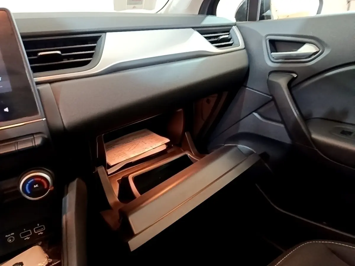 Intérieur noir du Renault Captur 2021 vu côté passager, boîte à gants ouverte avec documents visibles.