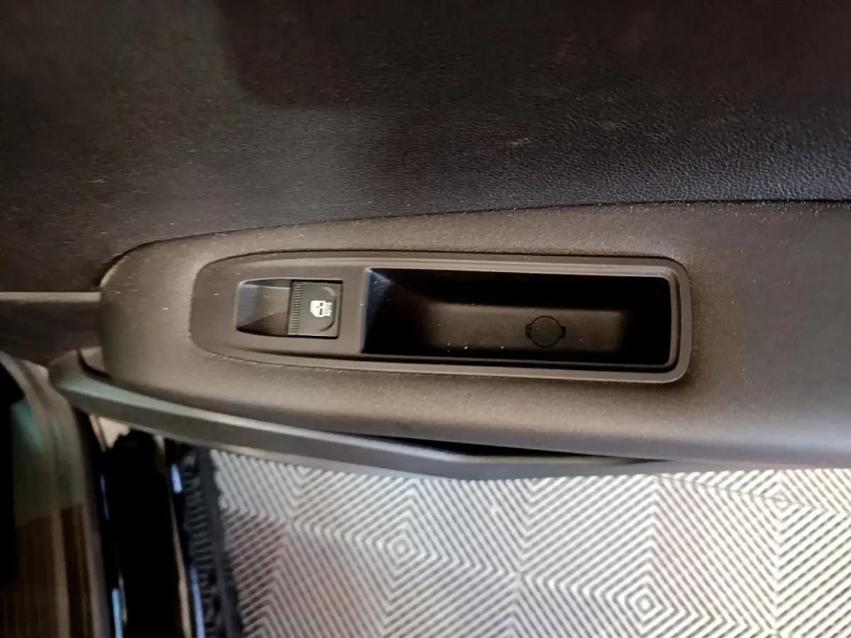 Gros plan sur la commande de verrouillage de porte intérieure noire du côté gauche d’un Renault Captur noir 2021.
