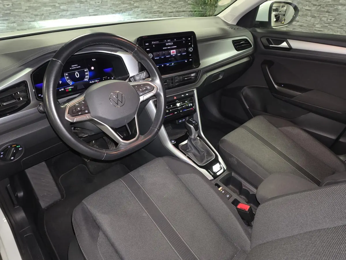 Vue intérieure côté conducteur du Volkswagen T-Roc 2022 avec tableau de bord digital et sellerie tissu noire.
