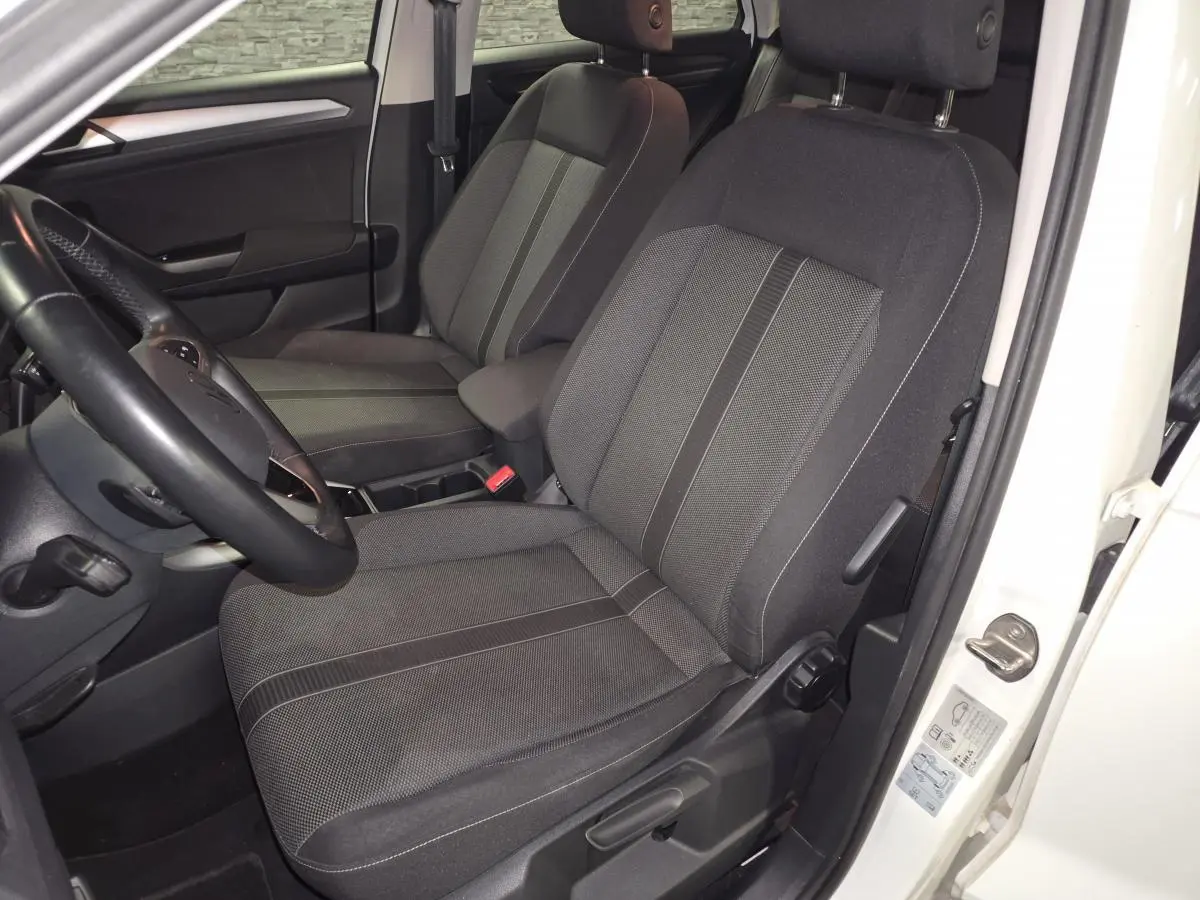 Vue intérieure côté conducteur du Volkswagen T-Roc blanc 2022, mettant en valeur les sièges en tissu noir et gris.