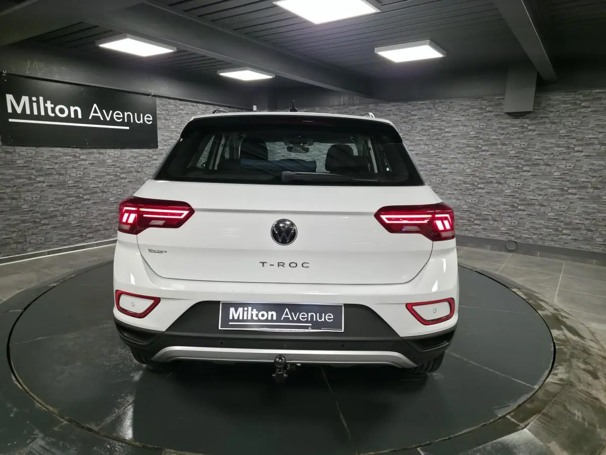 Vue arrière d'un Volkswagen T-Roc blanc avec feux LED allumés et dispositif d'attelage amovible visible.