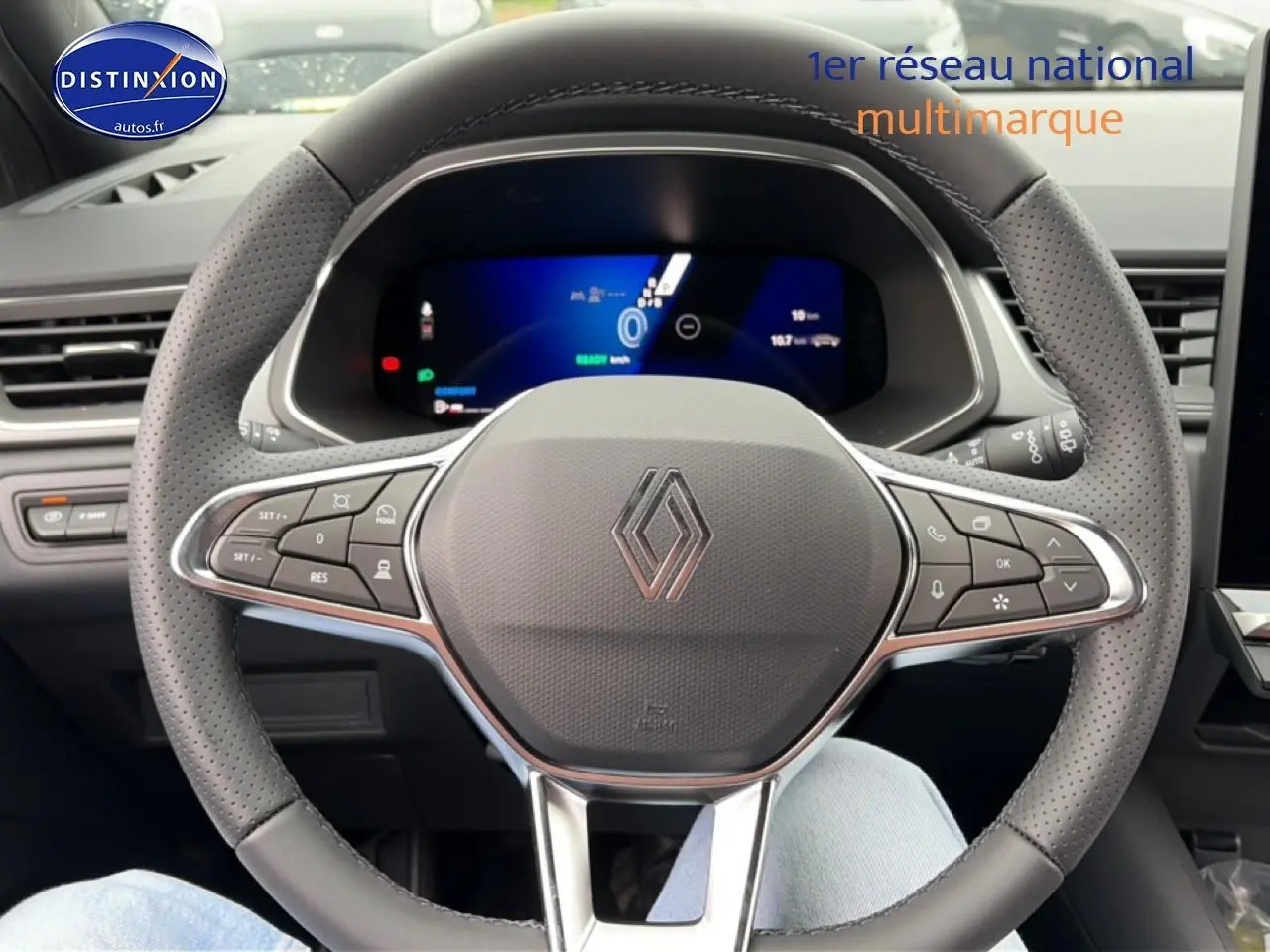 Vue rapprochée du volant en cuir perforé gris d’une Renault Symbioz 2026 avec tableau de bord numérique allumé.