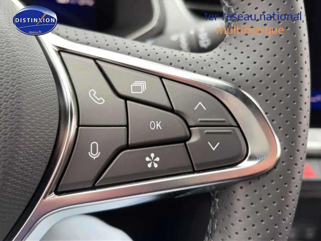 Gros plan sur les commandes multifonctions noires et chrome du volant perforé du Renault Symbioz gris schiste.