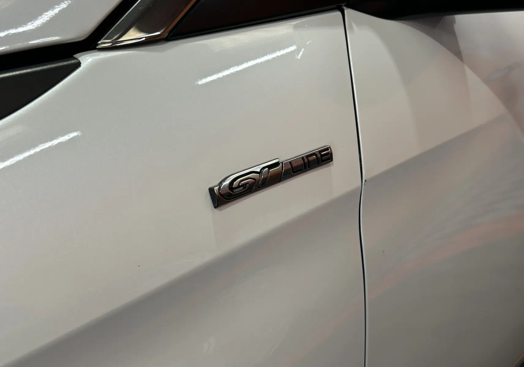 Gros plan sur l’emblème GT Line sur la porte blanche côté gauche du Peugeot 3008, finition sportive visible.