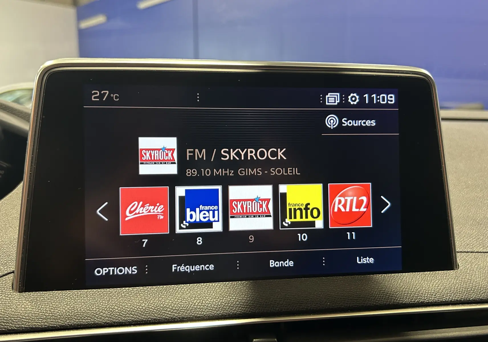 Écran central du tableau de bord d’un Peugeot 3008 blanc, affichant la radio FM sur Skyrock à 11h09.