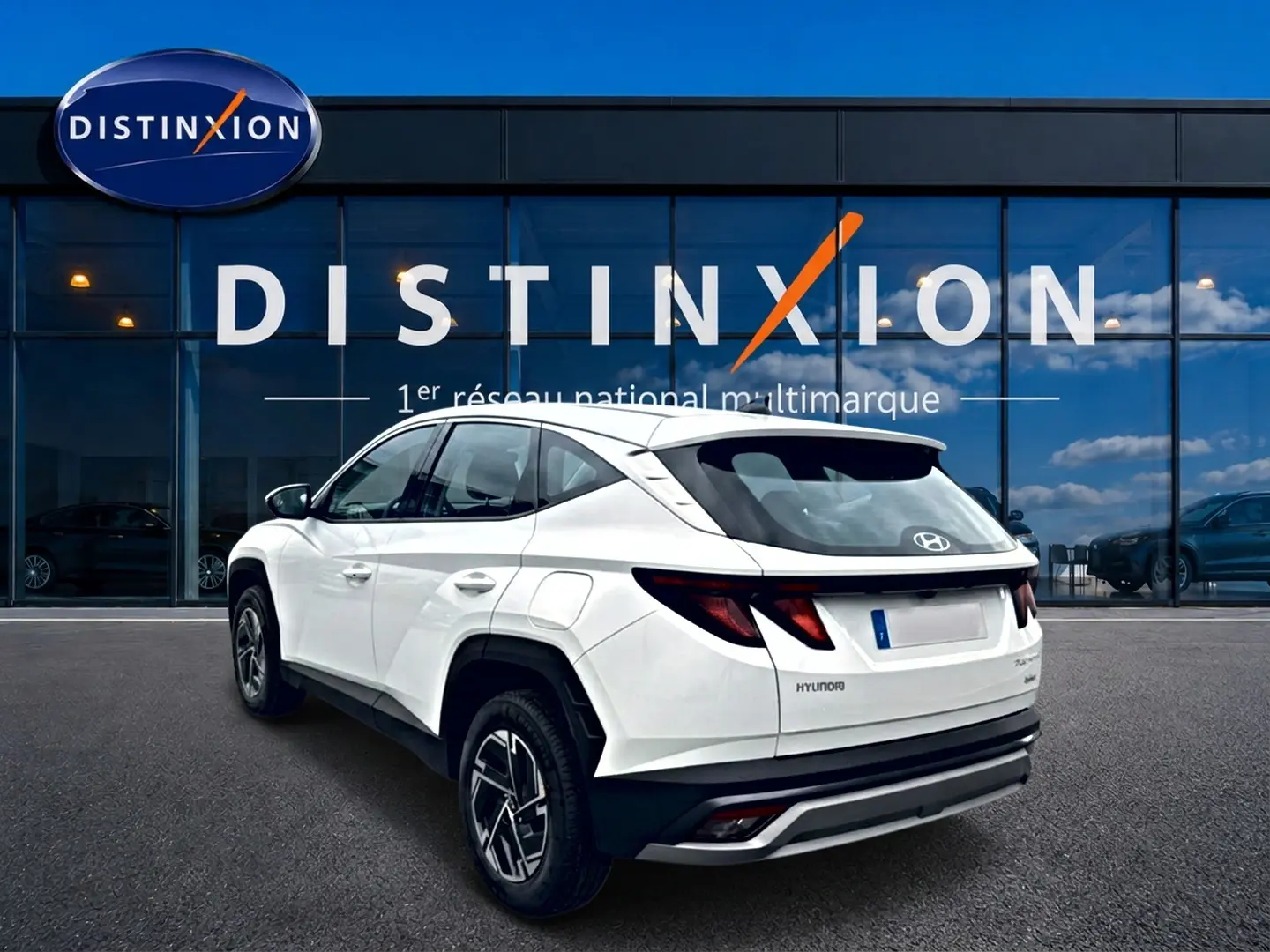 Vue 3/4 arrière droite d'un Hyundai Tucson blanc 2026 hybride, avec jantes alliage et feux arrière LED distinctifs.