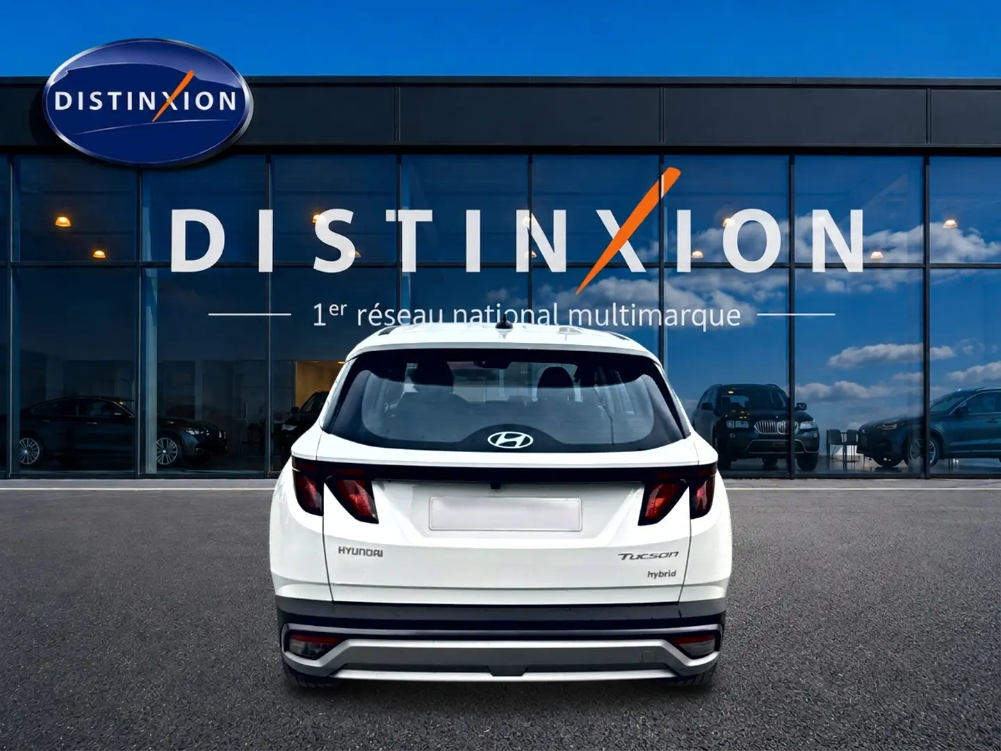 Vue arrière d'un Hyundai Tucson blanc hybride 2026, avec feux arrière sombres et logo Hyundai visible.
