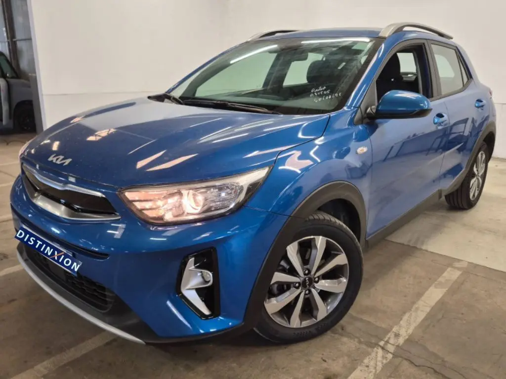 KIA Stonic bleu 2024 en 3/4 avant droit, avec phares allumés et jantes alliage distinctives.