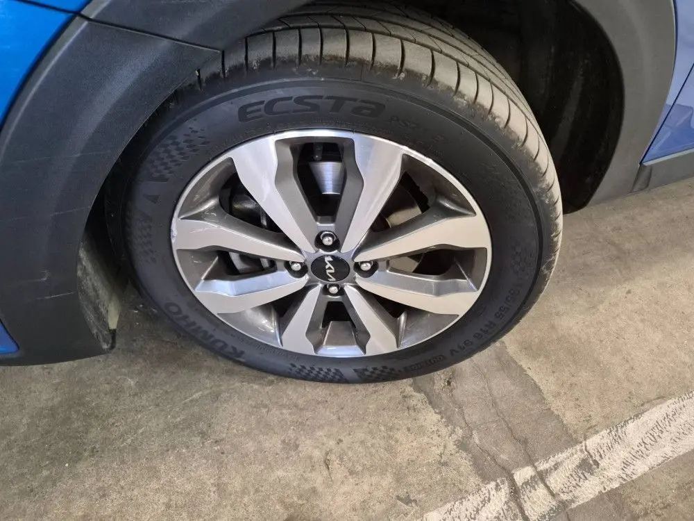Gros plan sur la roue avant droite d’un KIA Stonic bleu 2024 avec jante alliage et pneu Kumho Ecsta.