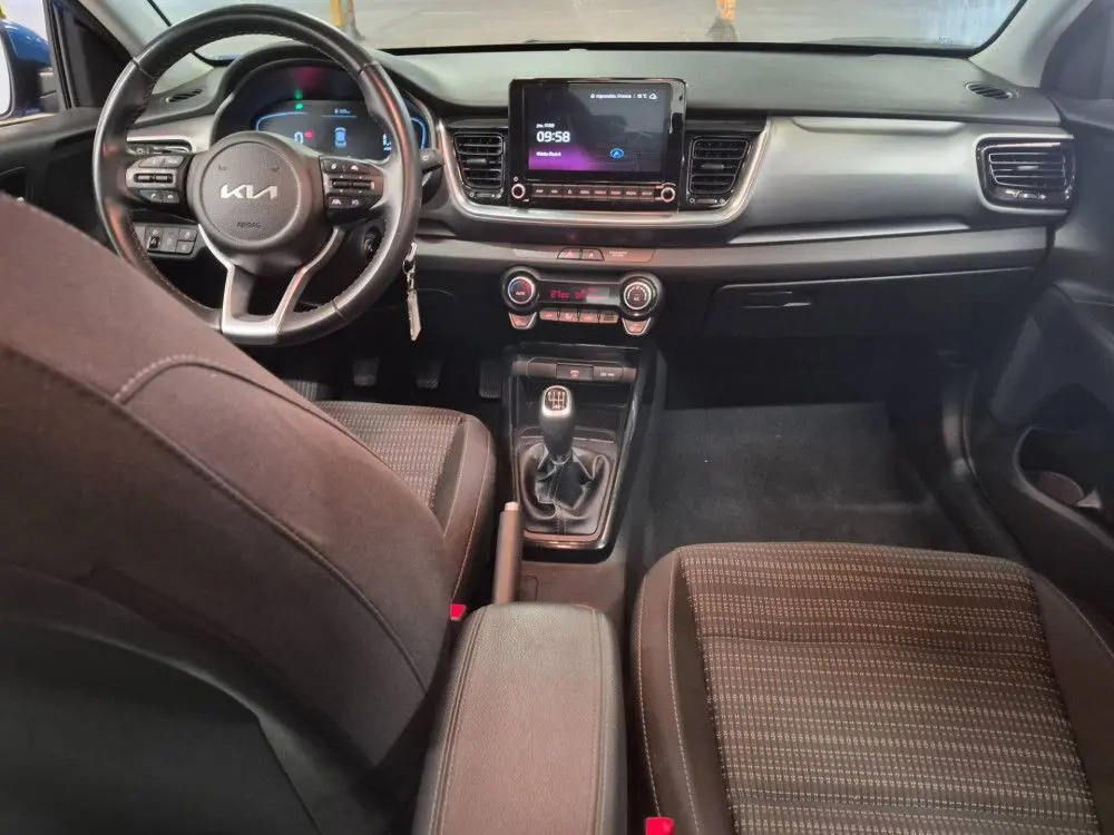 Vue intérieure du tableau de bord et console centrale du Kia Stonic bleu 2024 avec boîte manuelle et écran tactile.