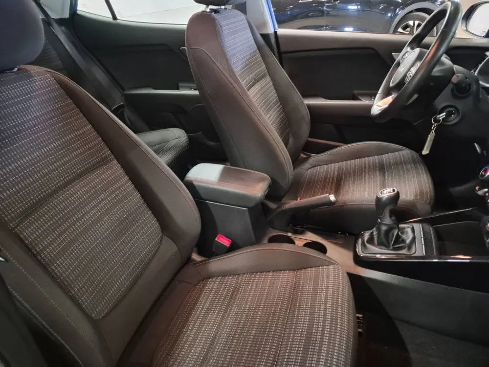 Vue intérieure côté conducteur du Kia Stonic 2024, sièges tissu gris avec boîte manuelle et volant à droite.