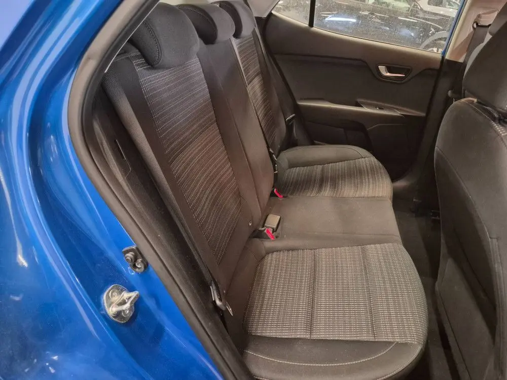 Vue intérieure des sièges arrière du KIA STONIC bleu 2024, avec tissu noir à motifs et ceinture de sécurité rouge visible.