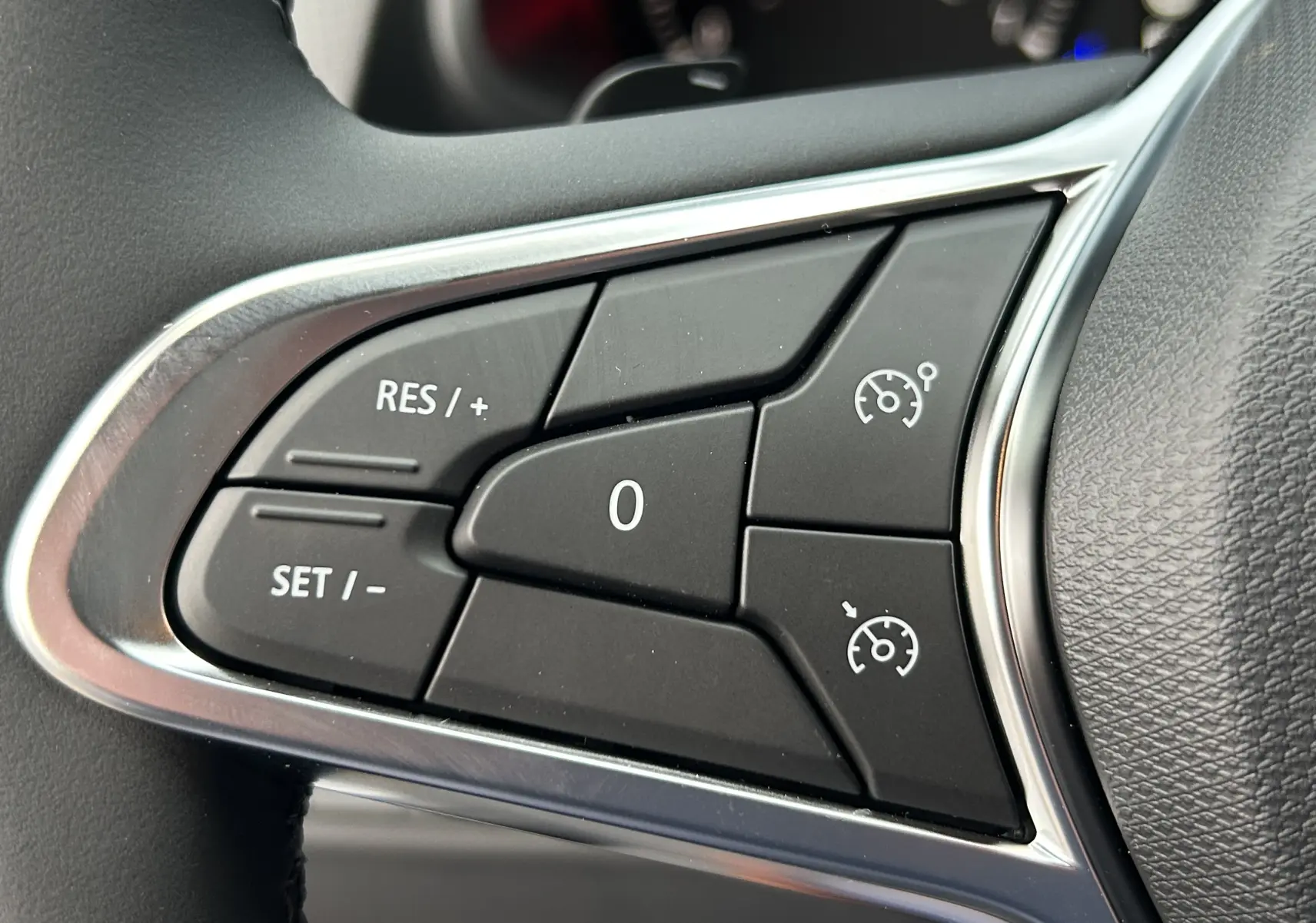 Gros plan sur les commandes de régulateur de vitesse au volant du Renault Trafic Fourgon gris Comète, version 2025.