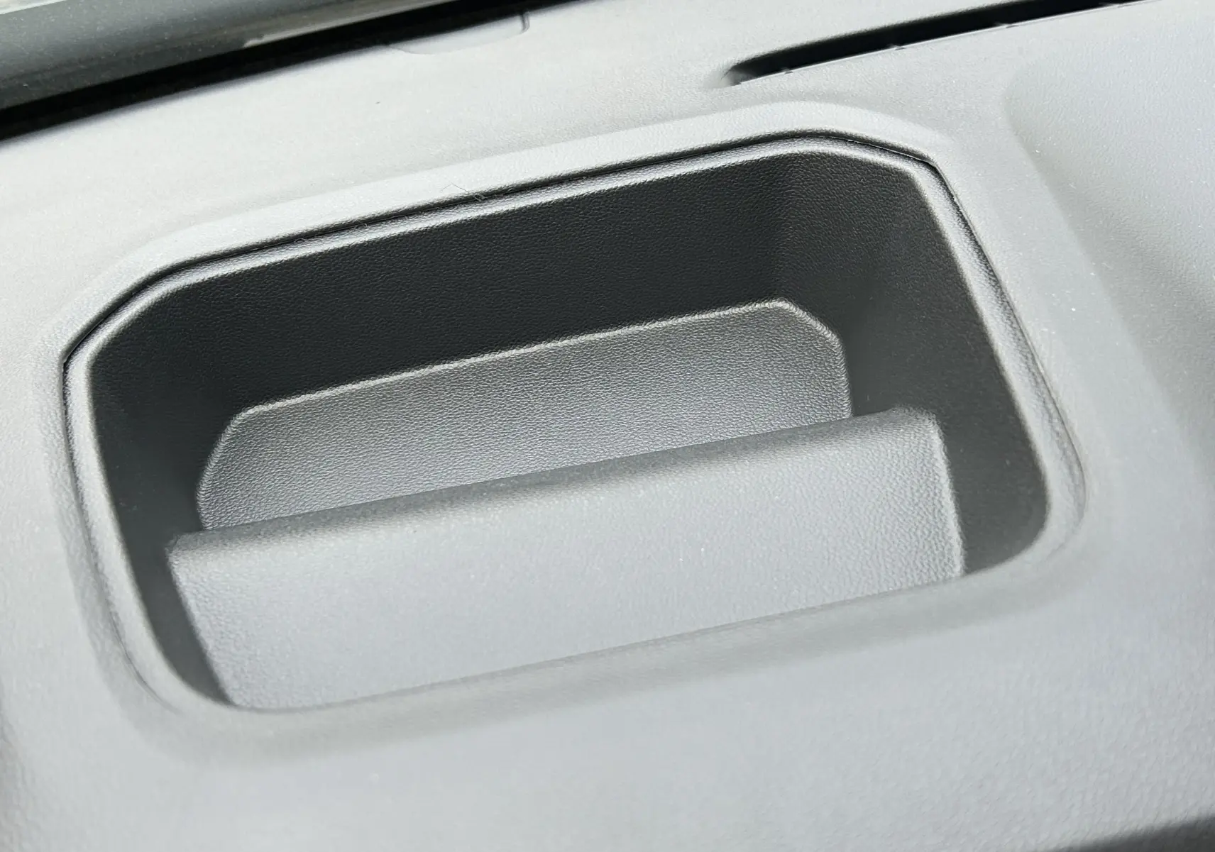 Gros plan sur un rangement en plastique noir intégré au tableau de bord du Renault Trafic Fourgon gris Comète.