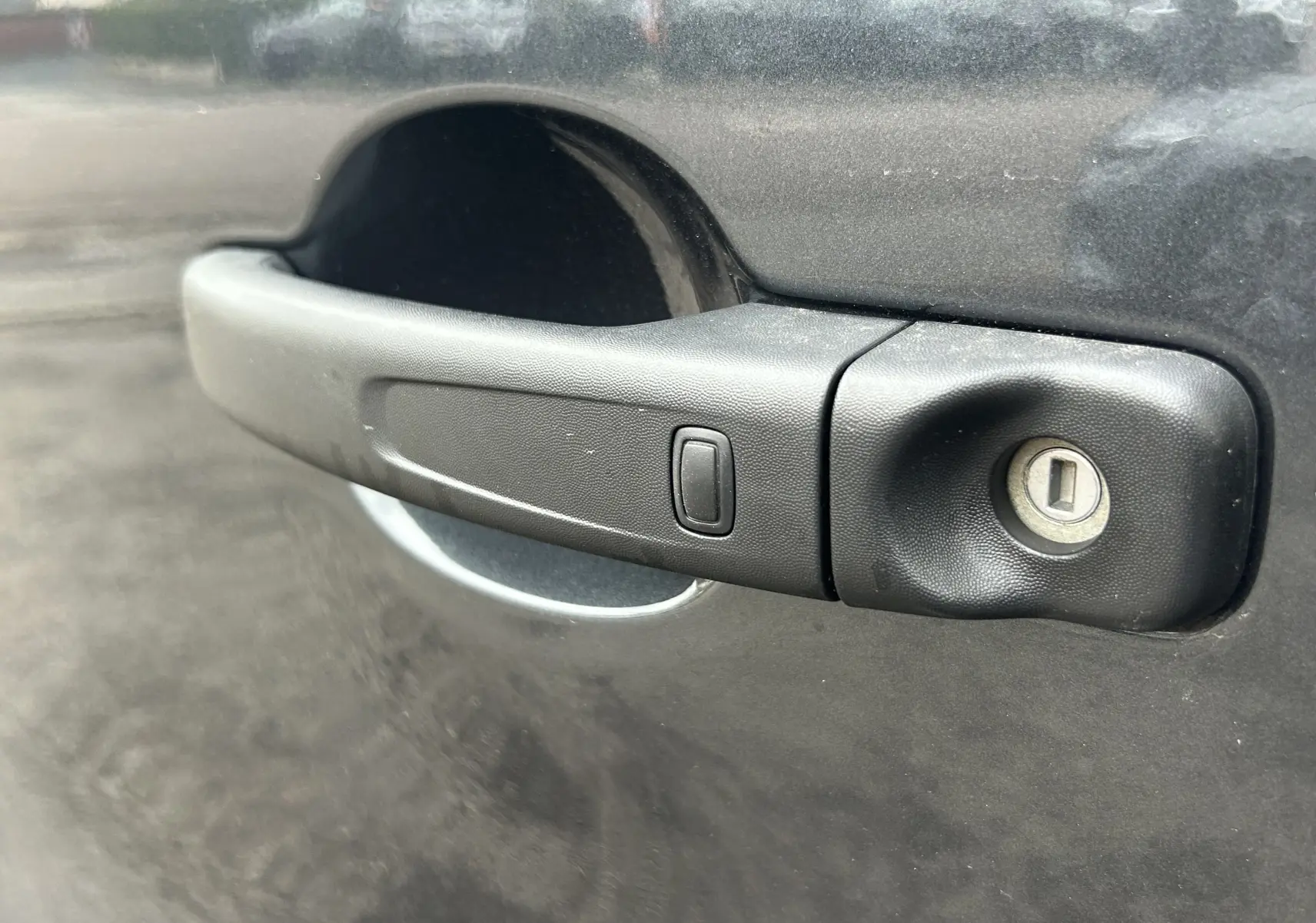 Poignée de porte noire en gros plan sur le côté gauche d'un Renault Trafic Fourgon gris Comète.