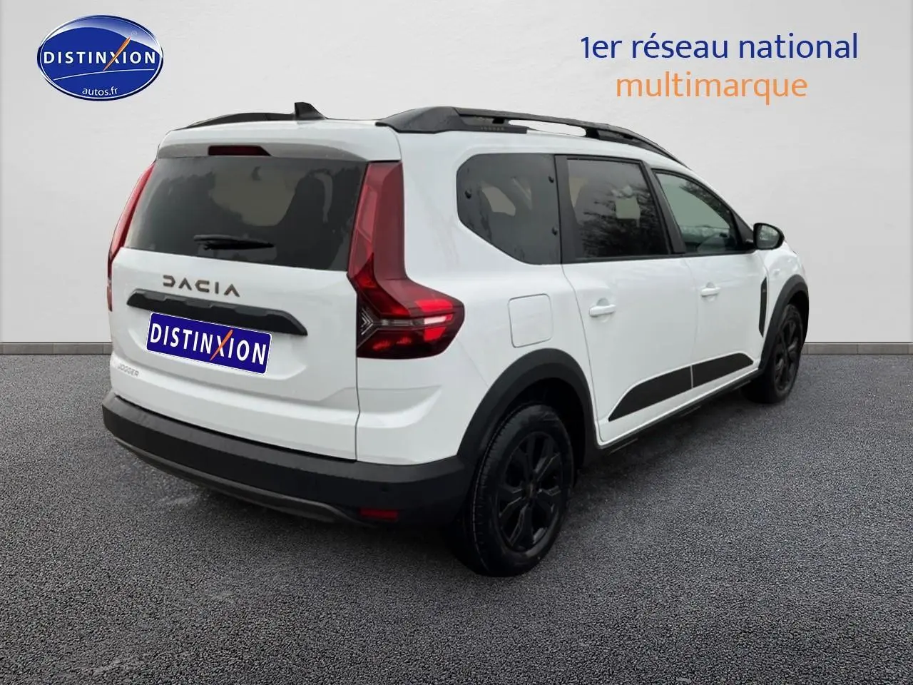 Vue 3/4 arrière droite d'un Dacia Jogger blanc avec barres de toit noires et vitres arrière surteintées.