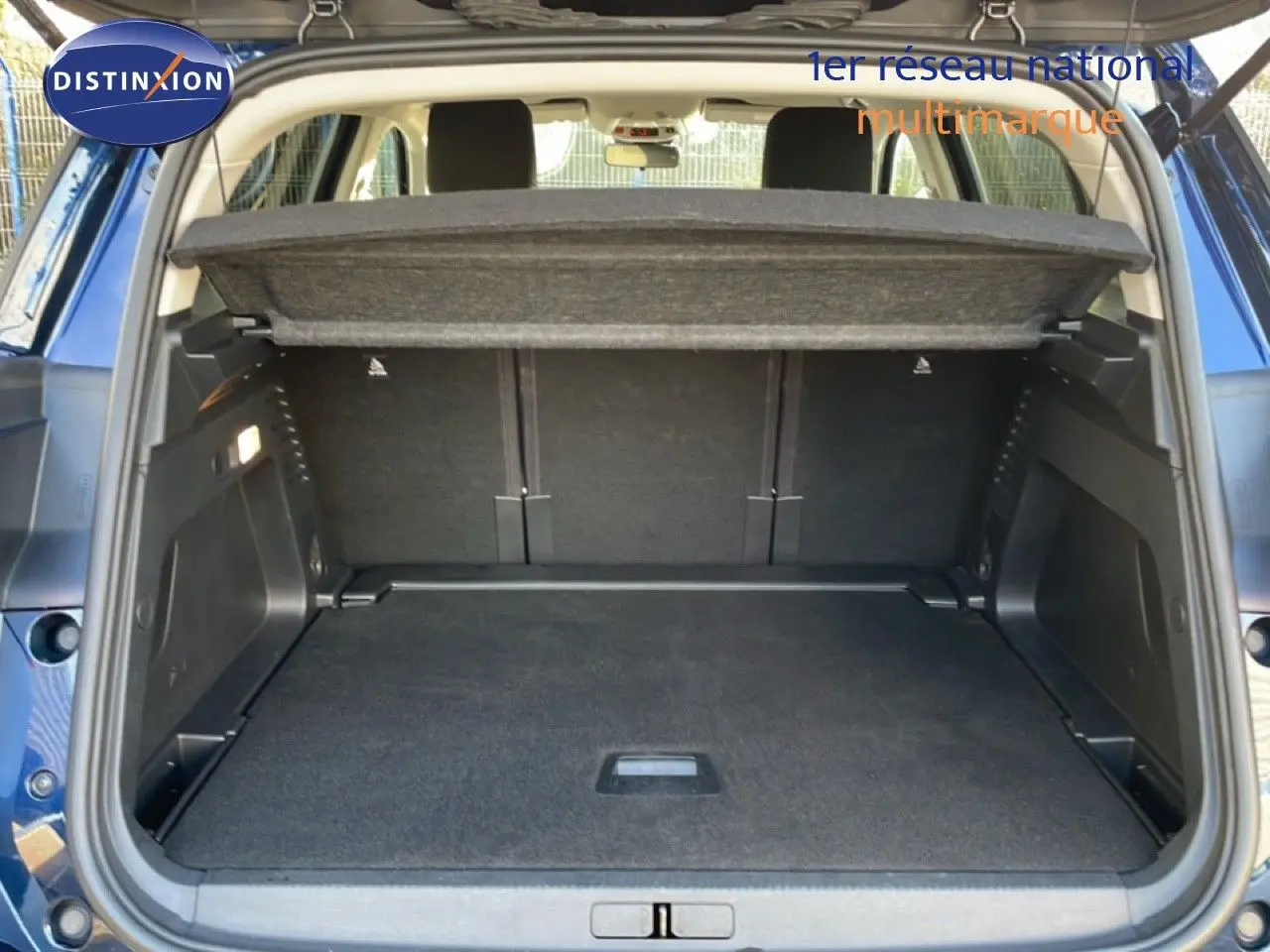 Coffre ouvert vu de l'arrière d'un Citroën C5 Aircross bleu Eclipse Metal, montrant l'espace de chargement et la tablette cache-bagages.