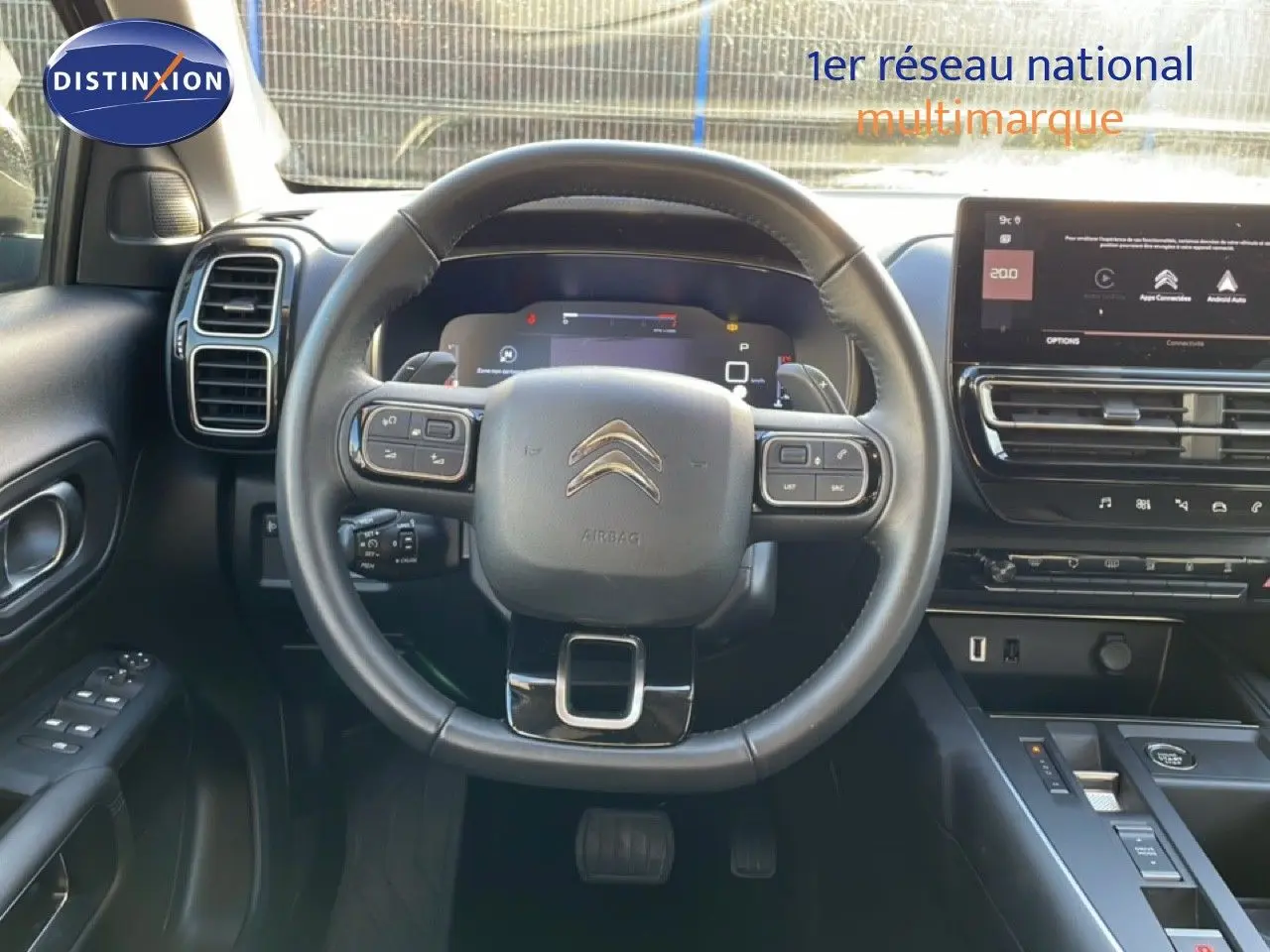 Vue intérieure centrée sur le volant noir du Citroën C5 Aircross 2025 avec tableau de bord digital et écran tactile.