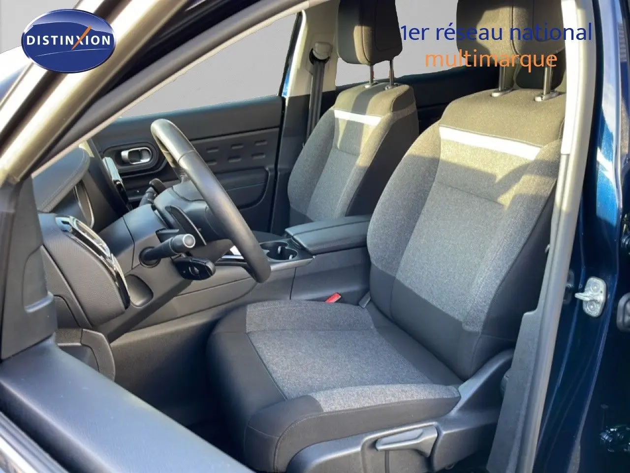Vue intérieure côté conducteur du Citroën C5 Aircross bleu Eclipse Métal, mettant en valeur les sièges tissu gris et la console centrale.