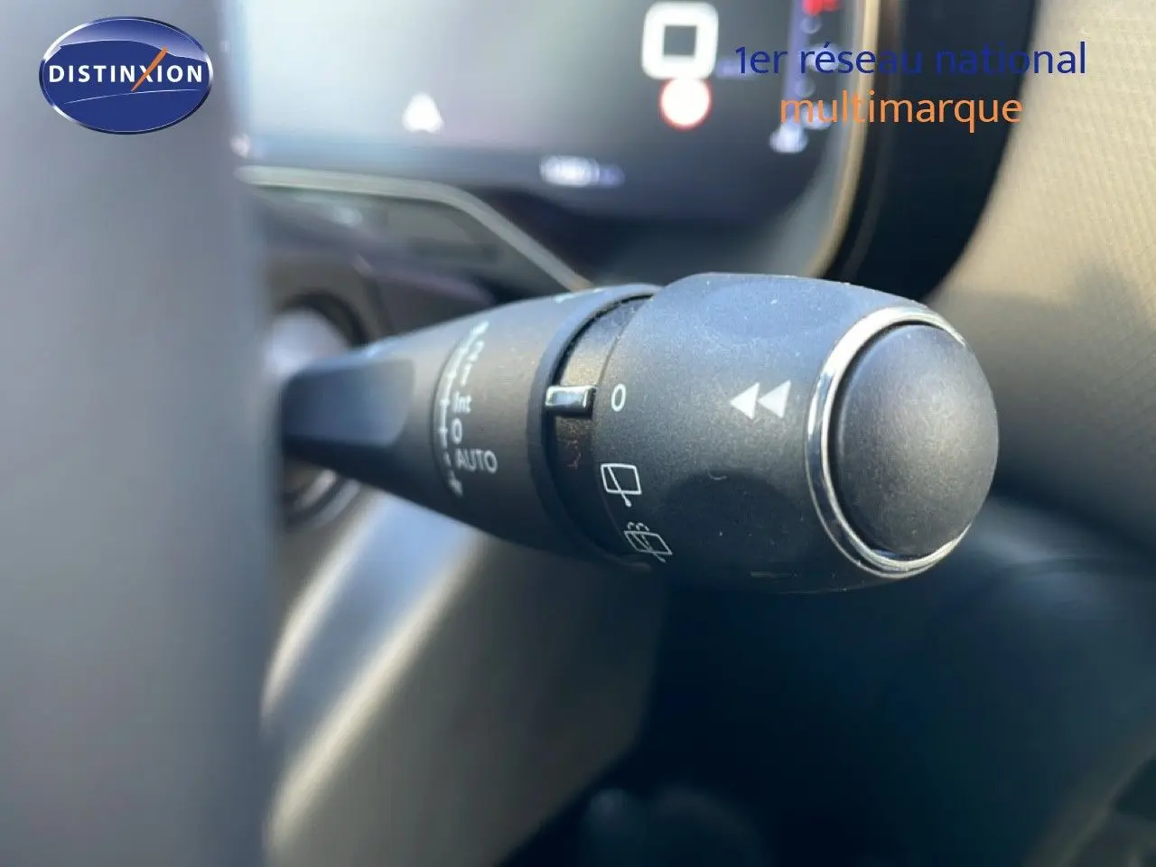 Gros plan sur la commande de l'essuie-glace du Citroën C5 Aircross 2025, intérieur noir avec tableau de bord numérique flou.