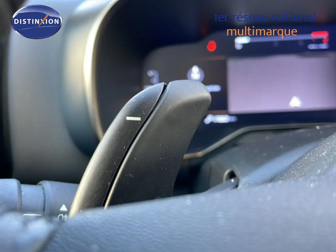 Gros plan sur la palette de changement de vitesse au volant du Citroën C5 Aircross bleu Eclipse Metal, tableau de bord flou en arrière-plan.