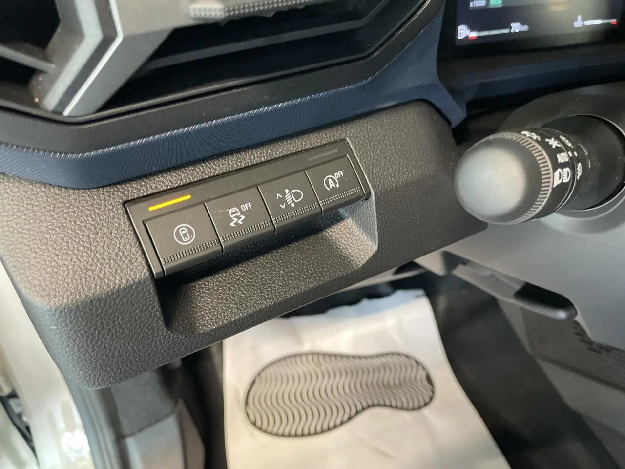 Gros plan sur les boutons de commande noirs à gauche du volant dans l’habitacle du Dacia Duster beige.