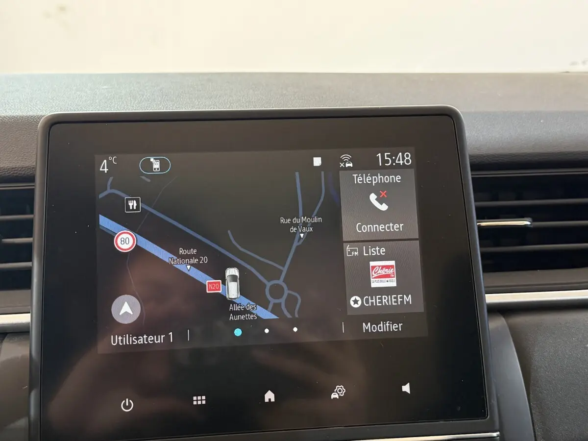 Écran tactile central du tableau de bord du Renault Captur bleu, affichant la navigation et les options multimédia.