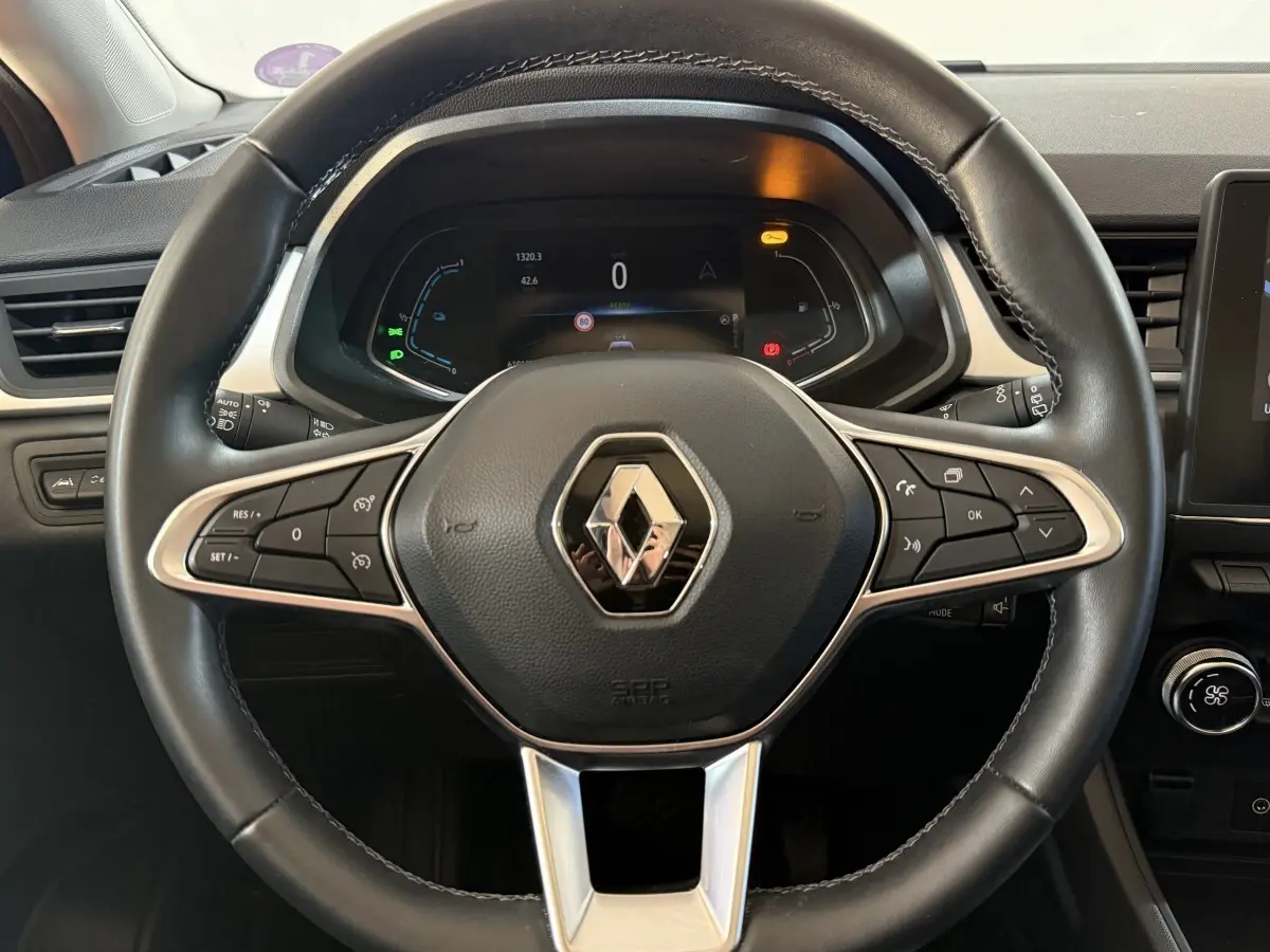 Vue rapprochée du volant en cuir synthétique noir du Renault Captur 2024 avec commandes multifonctions et tableau de bord numérique.