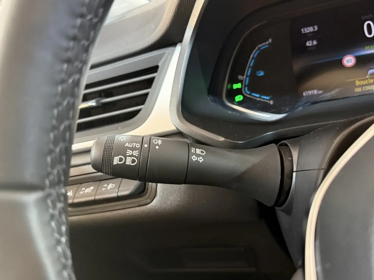Gros plan sur la commande des phares à gauche du volant dans l'habitacle du Renault Captur bleu 2024.