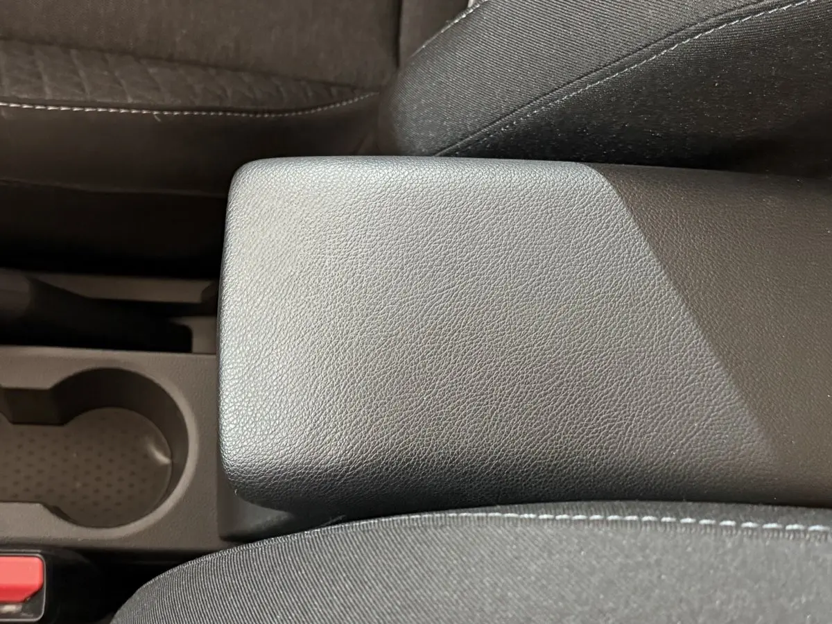 Gros plan sur l'accoudoir central en cuir synthétique noir et porte-gobelet du Renault Captur 2024.