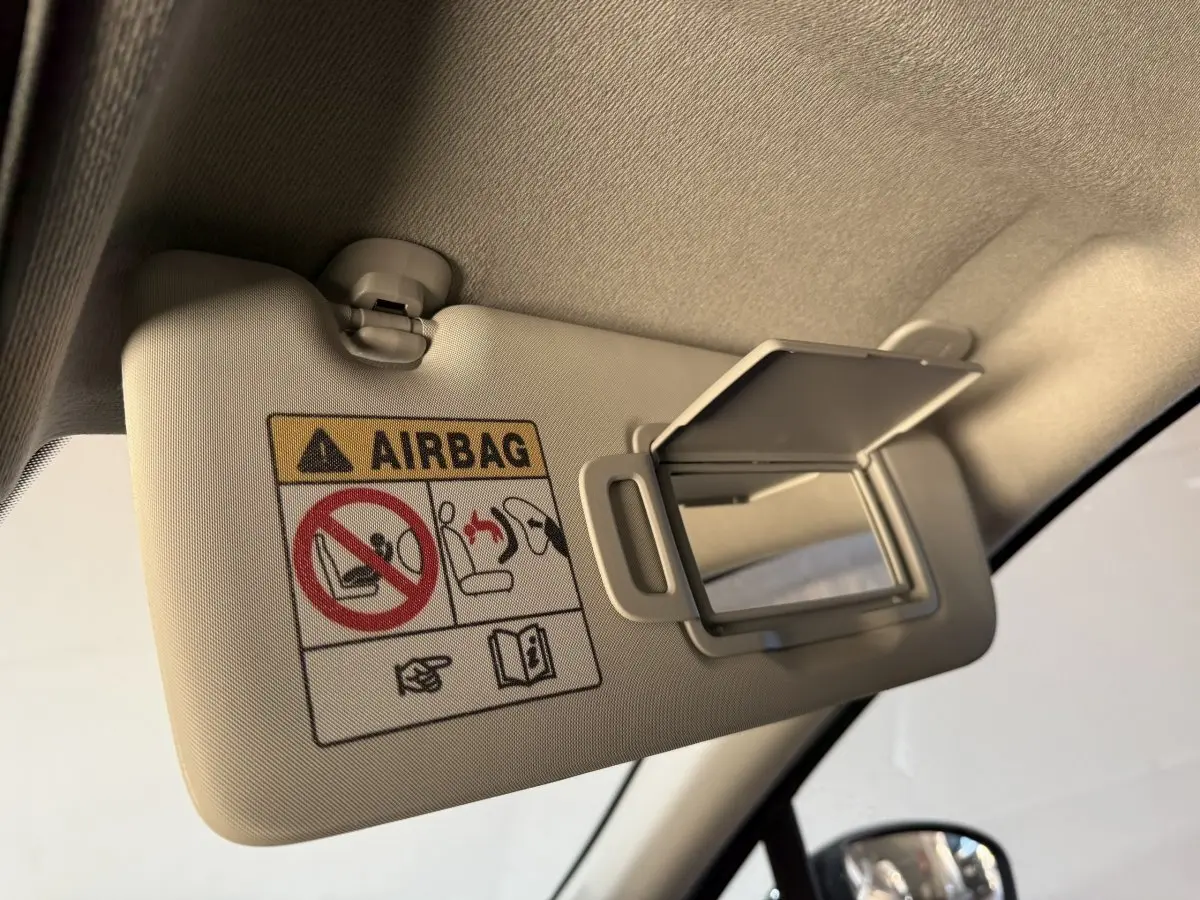 Détail du pare-soleil beige avec miroir ouvert et avertissement airbag dans un Renault Captur bleu, vue intérieure côté conducteur.