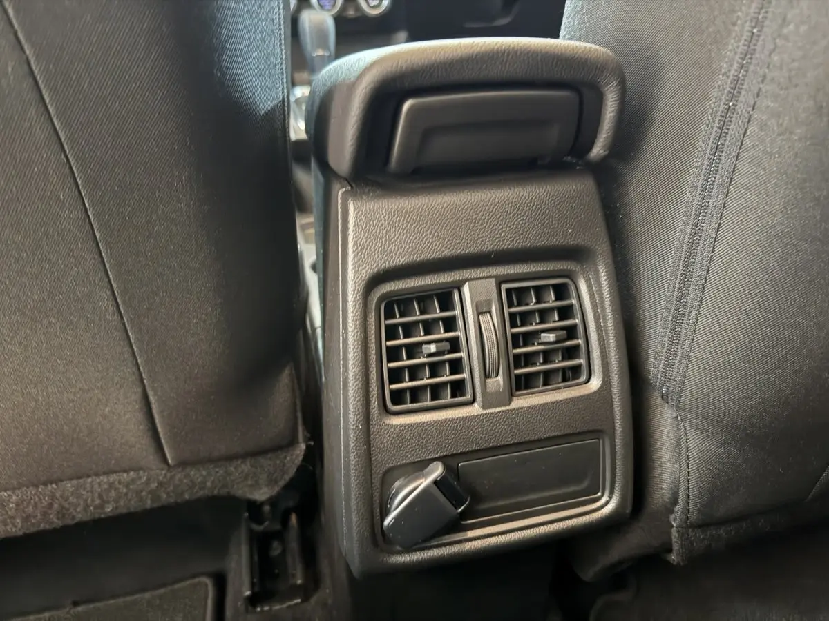Détail des aérateurs arrière et prise 12V entre les sièges noirs du Renault Captur bleu 2024.