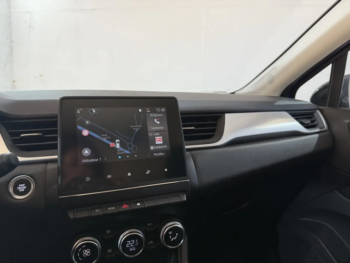Tableau de bord intérieur du Renault Captur bleu 2024, vue centrée sur l'écran tactile et commandes climatisation.