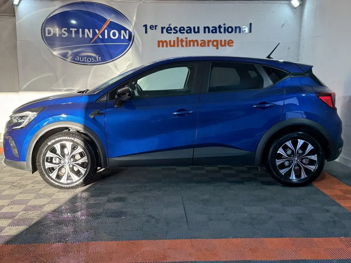 Profil gauche d'un Renault Captur bleu 2024 avec jantes alliage et protections noires sur les passages de roues.