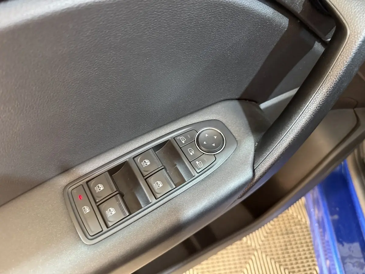 Gros plan sur la commande des vitres côté conducteur du Renault Captur bleu, avec boutons de réglage des rétroviseurs.