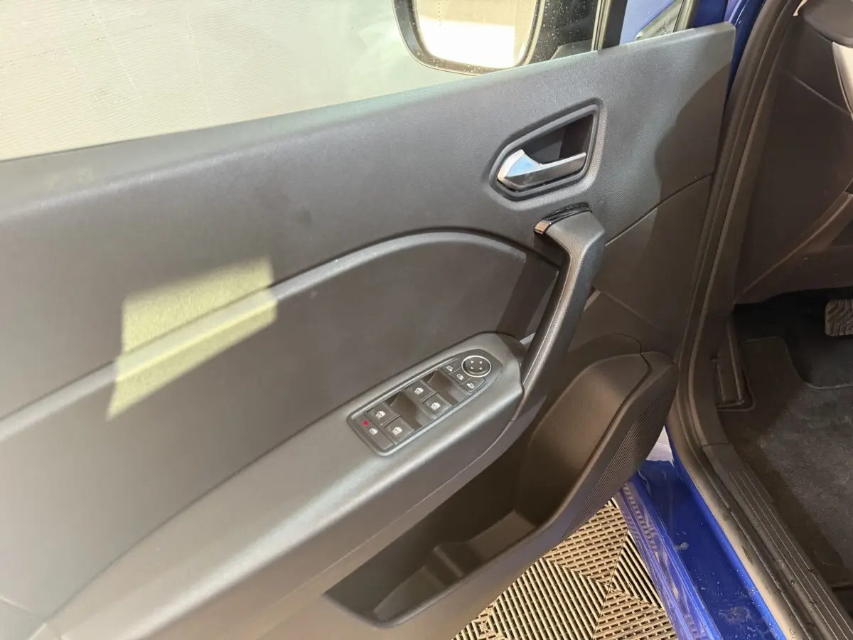 Vue rapprochée de la porte avant gauche noire du Renault Captur bleu 2024 avec commandes électriques des vitres.