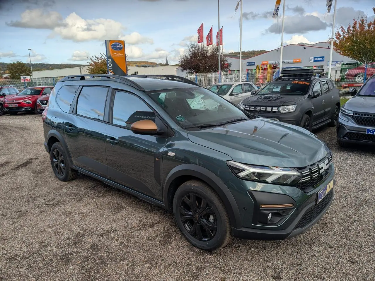 Vue 3/4 avant droit du Dacia Jogger 2025 vert métallisé avec rétroviseurs brun cuivré et jantes noires.