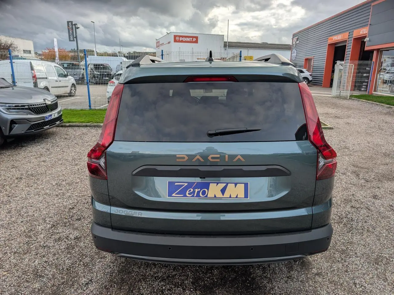 Vue arrière d'un Dacia Jogger vert métallisé avec logo brun cuivré et feux verticaux distinctifs, stationné en extérieur.