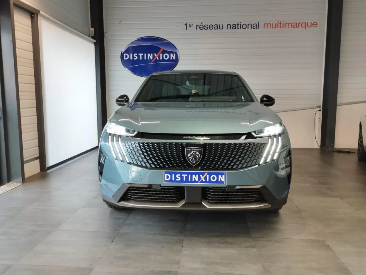 Vue avant d'un Peugeot 3008 Bleu Azul 2025 avec calandre noire et feux LED à griffes allumés en intérieur showroom.