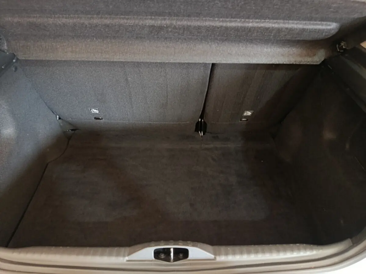 Coffre ouvert vu de face, intérieur noir, banquette arrière rabattue partiellement, Citroën C3 blanc 2020.