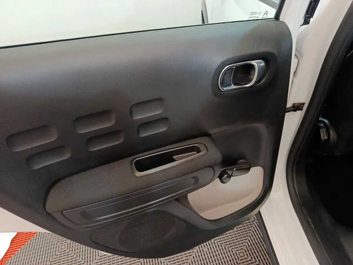 Vue rapprochée de la porte arrière droite noire et blanche de la Citroën C3 2020 avec poignée manuelle de vitre.